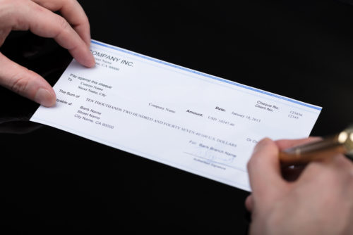 A closeup of a man signing a check.