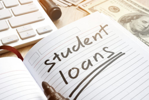 A handwritten note in a notebook reads "student loans."