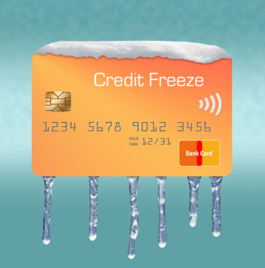 Ice and snow cover a mock credit card labeled "credit freeze" to depict a freeze on someones credit card.