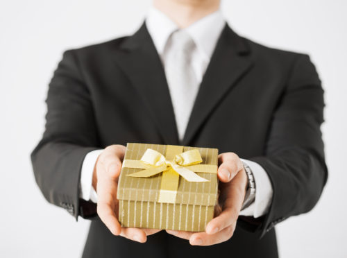 A businessman holding out a gift box.
