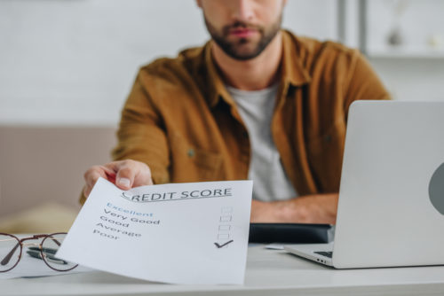 A man handing a person behind the camera a document labeled "credit score" with a section "poor" checked off.