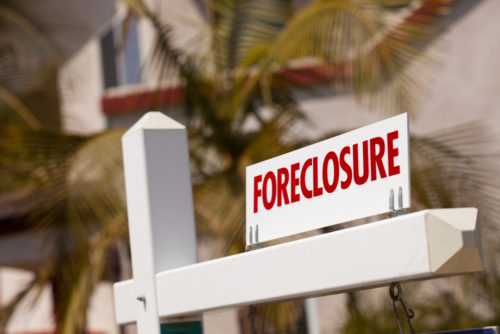 A close up of a foreclosure sign in front of a house.