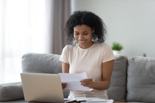 A woman in her 30s looking happy at her student loan bill.