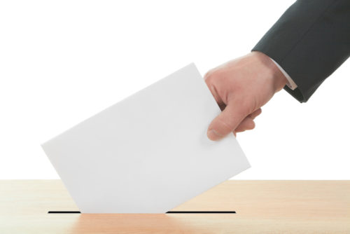 A man putting a ballot in a ballot box.