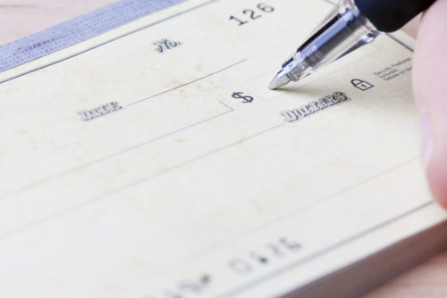 A closeup of a pen filling out a check.