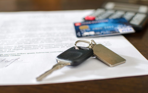 A car loan sits under a set of keys and a credit card.