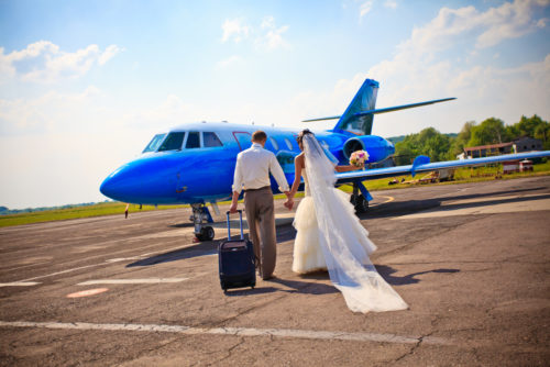 A couple walking toward an airplane, going on their honeymoon.