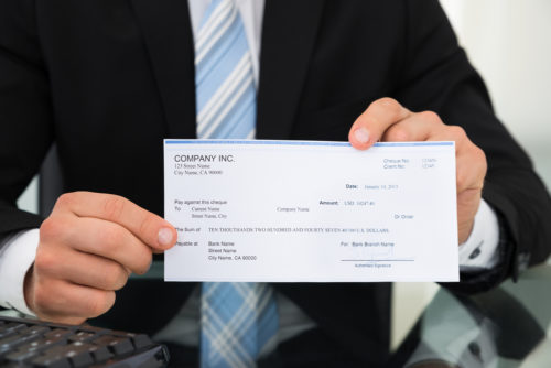 An image of a businessman holding up a check.