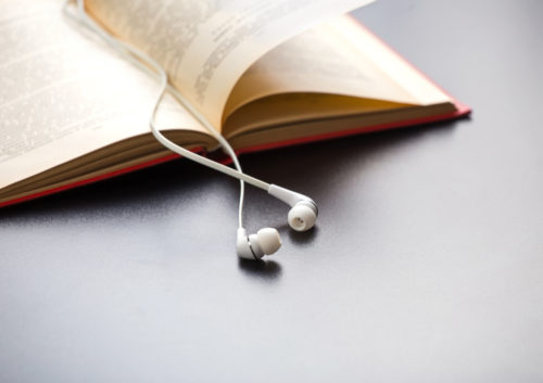 Headphones lie down the spine of an open book.