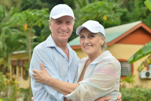 A retired couple hugging outdoors.