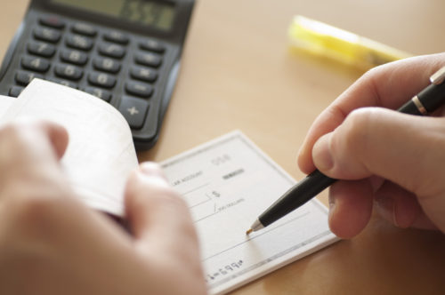 A close up of a hand writing a check.