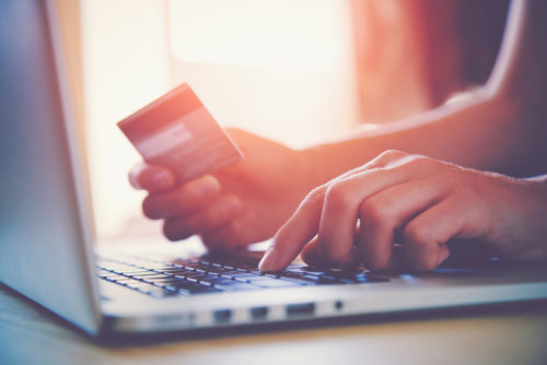 A person checking their available credit on their laptop while holding their credit card.