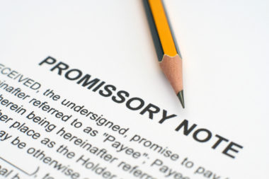 A pencil sits on top of a document labeled "Promissory Note."