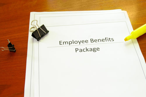 A highlighter and paperclips sit on top of a document labeled "employee benefits package."