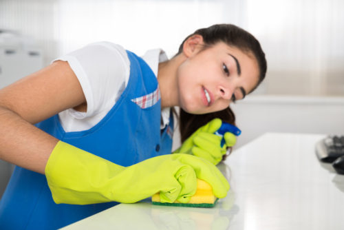 A housekeeper cleaning a surface with a sponge.