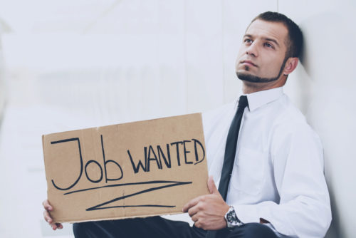 An unemployed man holding a cardboard sign that reads "job wanted."