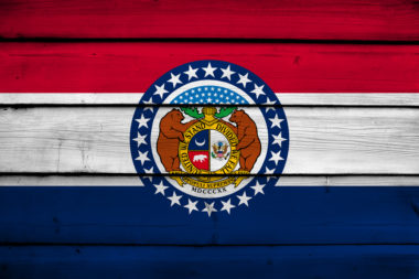 An image of the Missouri state flag on a wooden background.
