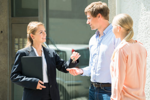 A realtor hands a couple the keys to their new home.