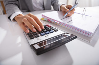 A closeup of a man estimating a budget on a calculator.