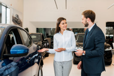 A car dealer showing a man around in a showroom.