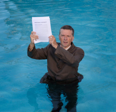 A man holding a mortgage document standing in the water.