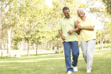 A retired couple strolling though a park.