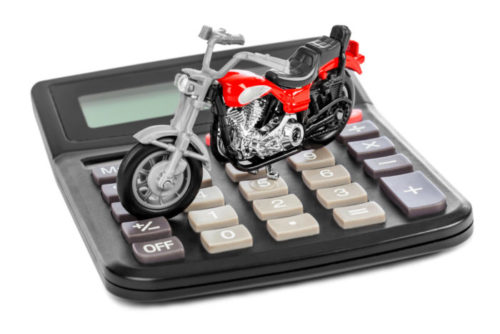 A tiny model motorcycle sitting on top of a calculator.