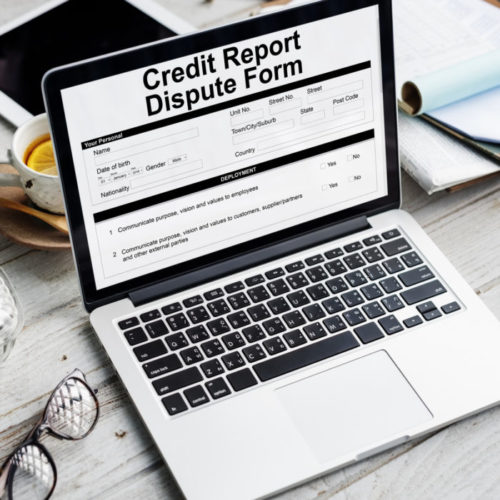 A laptop displays a credit report dispute form.