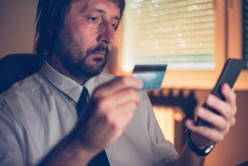 A man holding his smartphone in one hand and a credit card in the other.