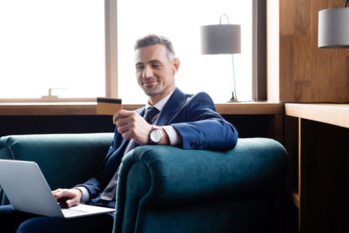A happy man smiles as he is looking at his credit card.