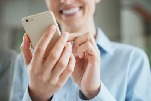 A smiling woman using her smartphone.