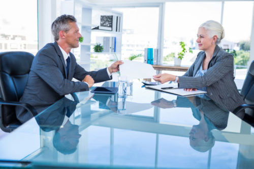 A financial advisor hands a document to a client.