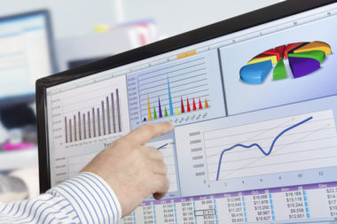 A man analyzing financial graphs and data on a computer.