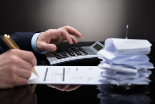 A debt collector calculates the debt of a client on a calculator and pen.