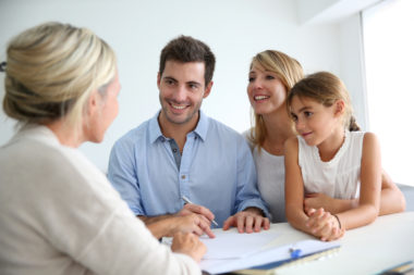 A mortgage agent speaking to a smiling family.
