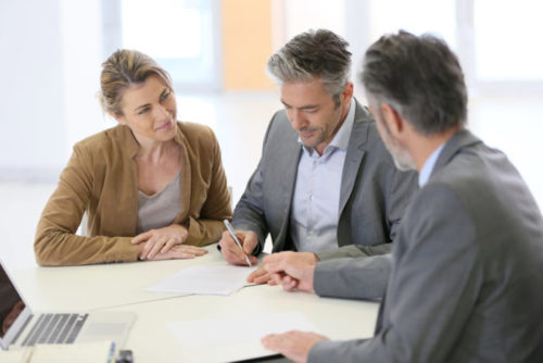 A banker showing where a couple needs to sign on a document.