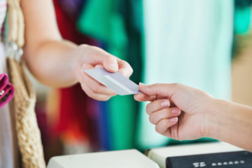 A person handing a store clerk their credit card.