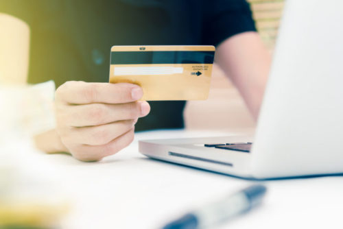 A person holds their credit card while shopping online.