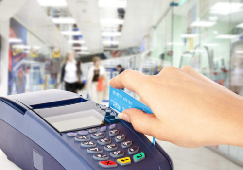 A closeup of a person swiping a credit card through a payment terminal.