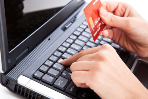 A person typing their credit card information on a laptop.