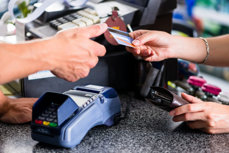 A woman handing a clerk her credit card.