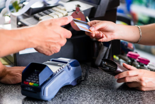 A woman handing a clerk her credit card.