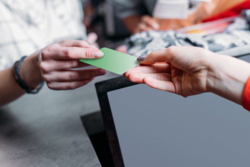 A woman handing a store clerk her credit card.