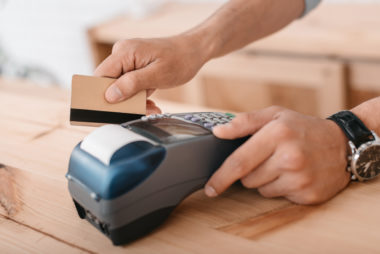 A person swiping a credit card through a payment terminal.