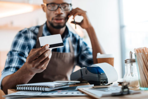 A handyman examines his credit card while speaking on the phone.