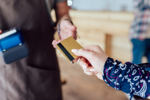 A woman handing her credit card to a store clerk.