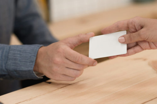 A woman handing a store clerk a credit card.