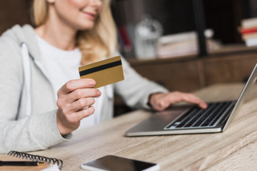 A woman shopping online while holding her credit card.