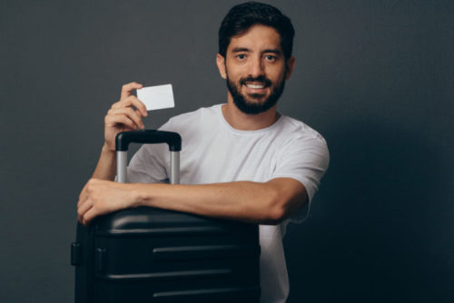 A traveling man holds his luggage and his credit card.