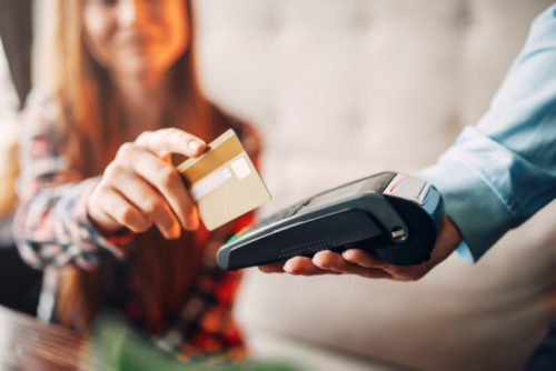 A waiter extends a payment toward a person for them to swipe their credit card through.